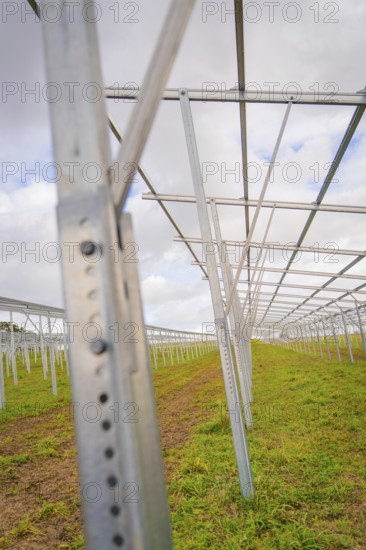 Empty metal structures for solar systems on a green field under cloudy sky, Energiewende,