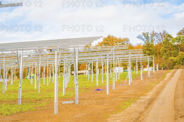 Extensive site with metal structures for solar panels and autumn sky, energy revolution,