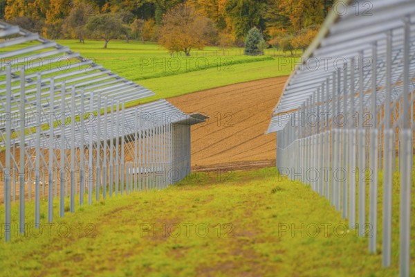Metal frame for solar panels in autumn landscape with green meadows, energy revolution,
