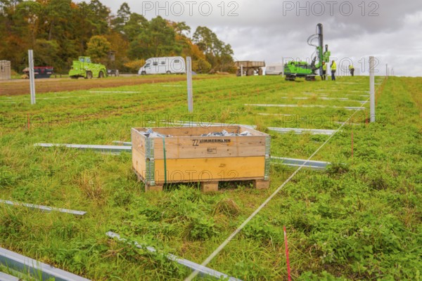 A wooden box in a meadow with building elements, surrounded by green grass and autumn landscape,