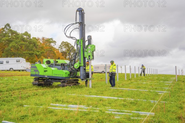 A drilling rig is operated by workers on a green field in autumn, Energiewende, construction of PV