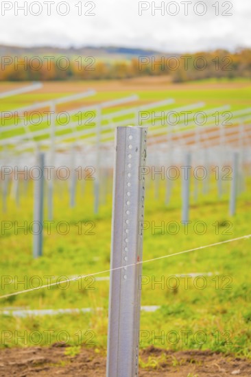 Close-up of a metal rod that is part of a larger field installation, with blurred landscape in the