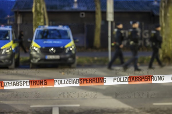 Flutter tape with the inscription police barrier. Behind them, police vehicles. Stuttgart,