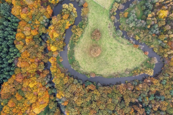 The river Hunte, which surrounds a green island with autumn-colored trees, viewed from the air,