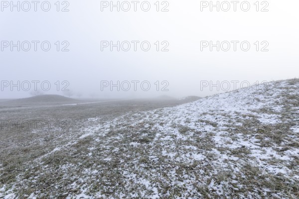 Mystical Celtic burial mounds in winter fog near Erkenbrechtsweiler. Snowy historic burial sites on