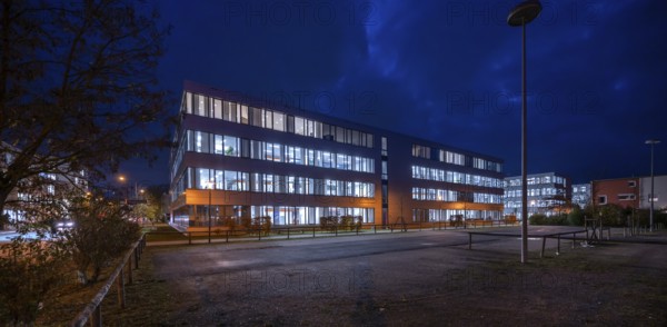 Siemens office buildings illuminated in the evening, empty parking spaces in front, Erlangen,