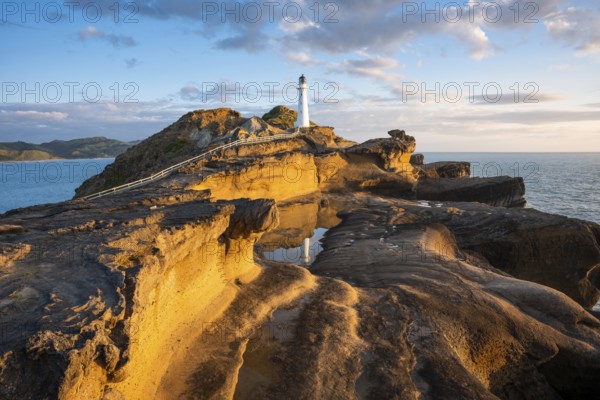 Castlepoint lighthouse on a rock, sea, sunrise. Castlepoint, Wairarapa Coast, Wellington Region,