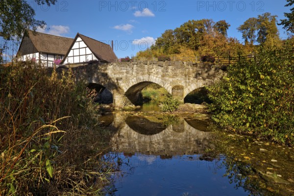 The river Hönne with the old Hönnetalbrücke in autumn with half-timbered house in Volkringhausen,
