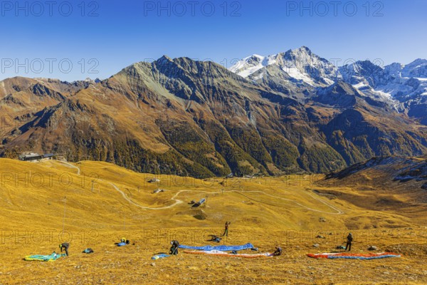 Paragliders prepare their start, summit of the Corne de Sorebois, with the backdrop of the Valais