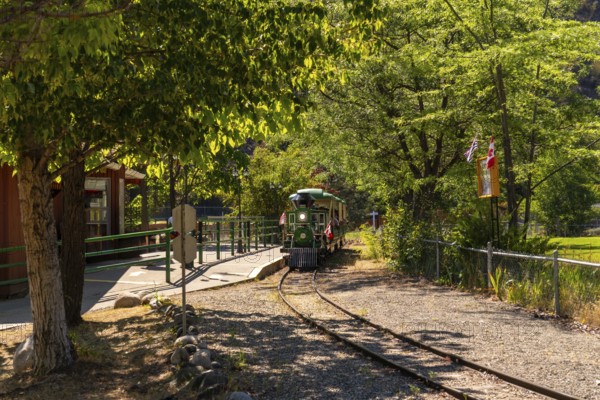 Green and yellow miniature train approaching the station in a sunny summer day in kamloops, british