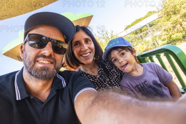 Happy family consisting of a father, mother, and son taking a selfie while enjoying a ride on a