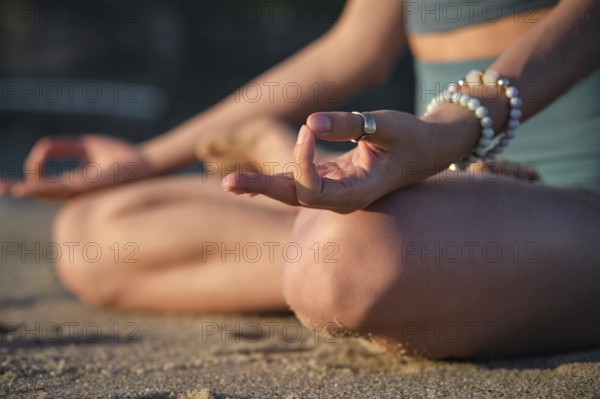 Woman meditates in Padmasana on the beach, using Chin mudra hand gesture in a tranquil setting