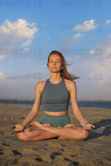 A woman performs Ashtanga Vinyasa yoga in Padmasana with Chin mudra on the beach, meditating