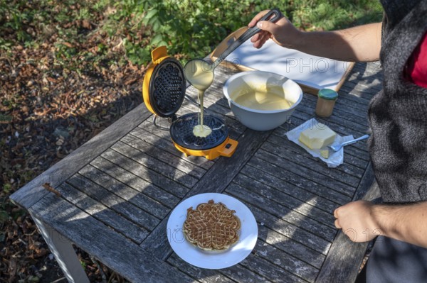 Preparation of waffles with a waffle iron on an outdoor garden table, Othenstorf,