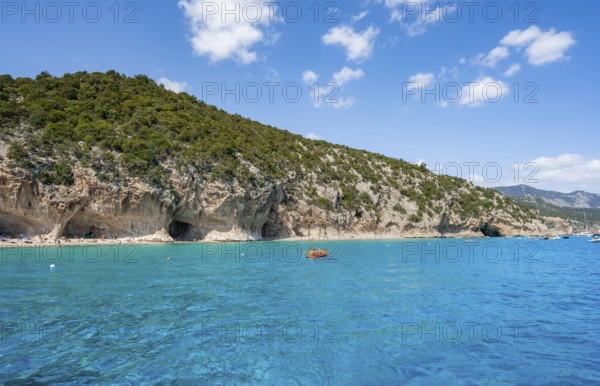 Kayakers in clear blue water, picturesque rocky coast, cliffs and Cala Luna beach, Golfo di Orosei,