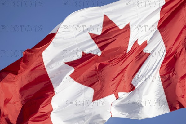 Red and white Canadian flag with a maple leaf waving in the air in downtown Toronto near Ontario
