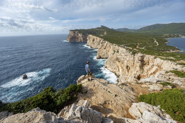 Tourist enjoying the view of steep cliffs by the sea, coastal landscape, cliffs on the Capo Caccia