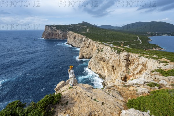 Tourist enjoying the view of steep cliffs by the sea, coastal landscape, cliffs on the Capo Caccia