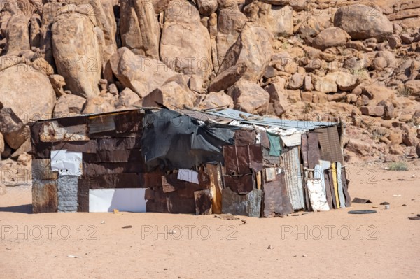 Simple poor huts made of corrugated iron and wood, desert landscape, barren landscape with hills of