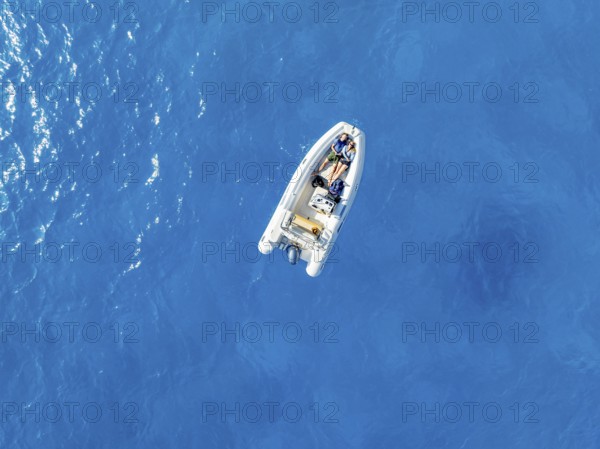 Young woman and young man lying in a motor boat on a blue sea, top-down, aerial view, Golfo di