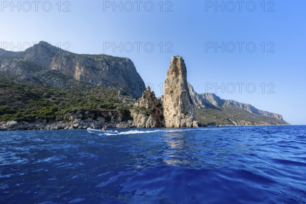 Picturesque rocky coast, cliffs with Pedra Longa pinnacle in the evening light, blue sea, Golfo di