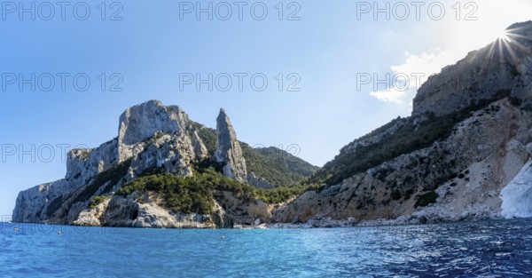 Picturesque rocky coast, cliffs with L'Aguglia pinnacle, blue sea and Cala Goloritzé beach, sun