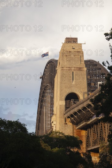Side view of Sydney Harbour Bridge at sunset with the Australian flag