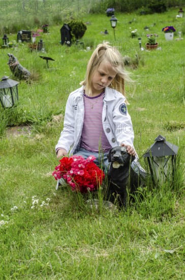 Grieving blonde 7-year-old girl at her dog's grave at pet cemetery in Ystad, Skåne County, Sweden,