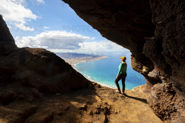 Tourist in the Cueva de las Cabras cave, young woman enjoying the view from the Risco de Famara