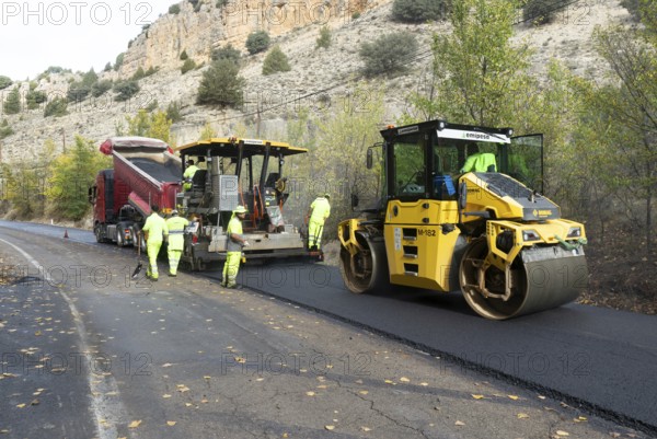 Asphalt road construction team of workers resurfacing tarmac in rural area, near Albarracin, Teruel