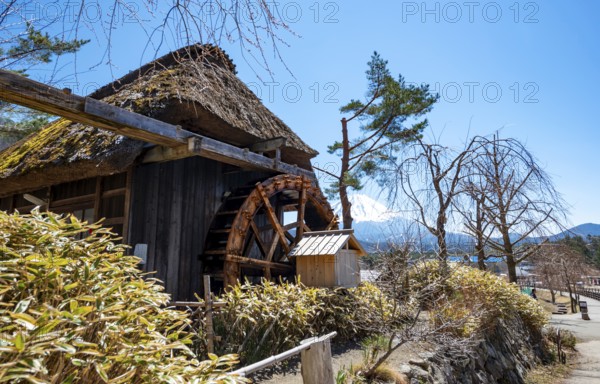 Iyashinosato open-air museum, old Japanese village with traditional houses, at the back volcano Mt.