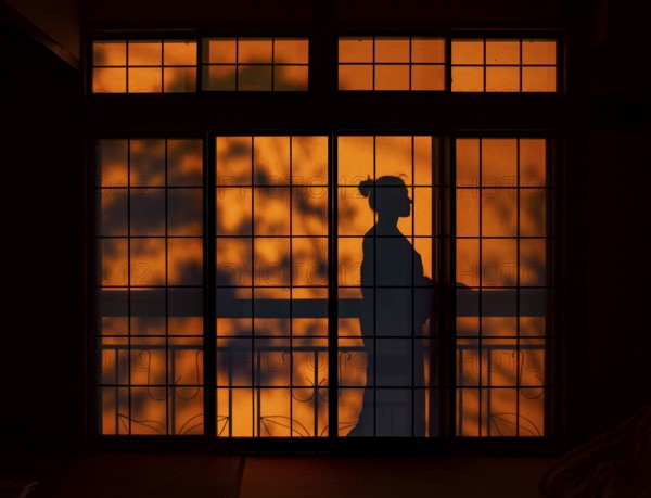 Shadows of a woman in kimono, on the balcony behind sliding shoji doors in a traditional Japanese