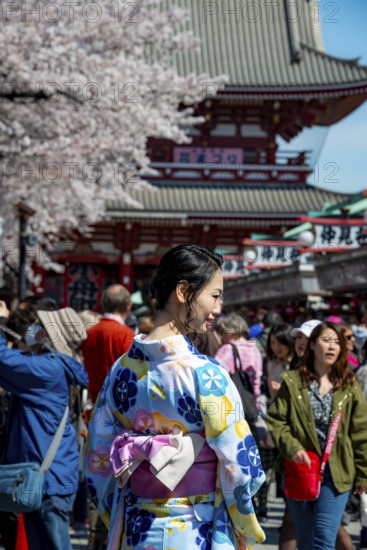 Young Japanese woman wearing kimono surrounded by numerous visitors on Nakamise-dori shopping
