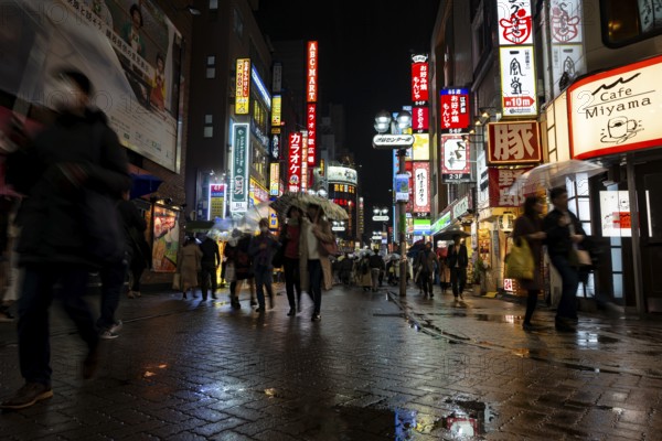 Busy pedestrian zone with many shopping centers and stores, illuminated with lots of neon signs at