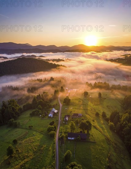 Sunrise over a fog covered village in a rural landscape, golden morning light, serene autumn