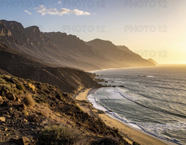 Desert landscape converges with ocean along a rugged coastal area, shore break at cliffs, blue