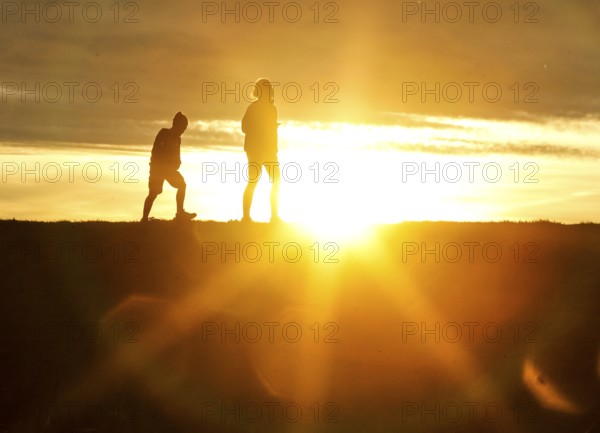 Woman and child walk across a dike on the island of Fehmarn at sunset, 13.10.2025, Fehmarn,