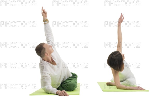 Couple in white sport tshirts and green trousers doing yoga exercises on green mats in studio
