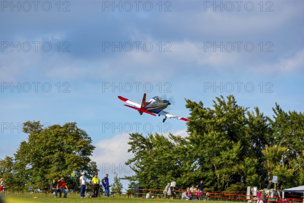 An RC model of a Pilatus PC-21 with advertising for the Swiss watch brand Breitling during a flight