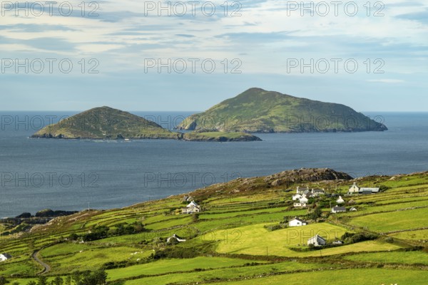 Elevated view over green meadows bordered by natural stone walls and typical cottages to the