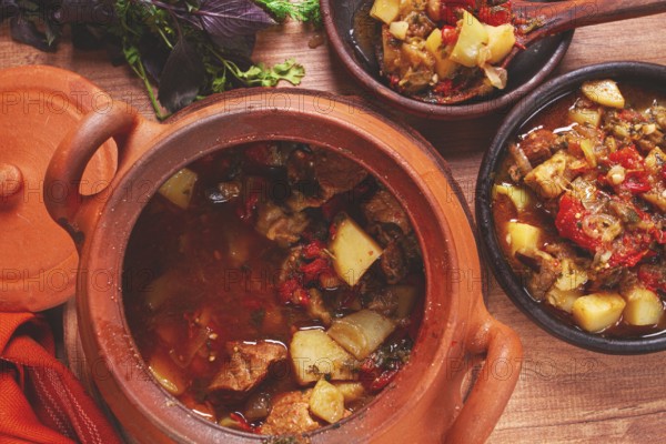 Chanakhi, a Georgian dish. in a clay pot, on a wooden table, stewed meat with vegetables, homemade,