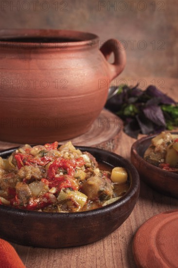 Chanakhi, a Georgian dish. in a clay pot, on a wooden table, stewed meat with vegetables, homemade,