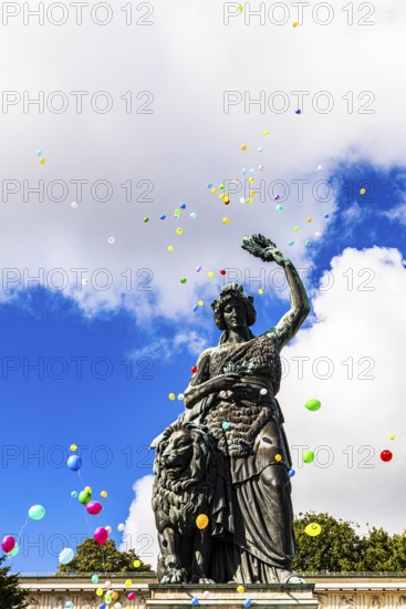 Colourful balloons rise high above the statue of Bavaria into the white-blue sky, grand finale of