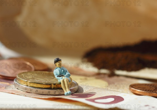 Miniature figure of a woman sitting on coins and banknotes, ground coffee in a filter bag in the
