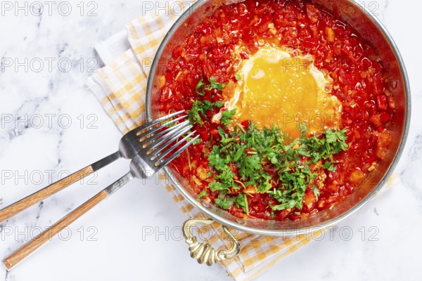 Traditional Turkish dish, scrambled eggs with tomatoes, Menemen, with herbs, in a frying pan,