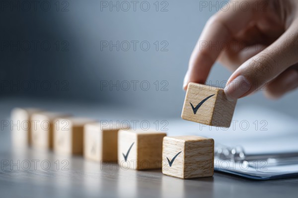 Checklist and task progress tracking concept. A hand placing the final checkmark on wooden blocks
