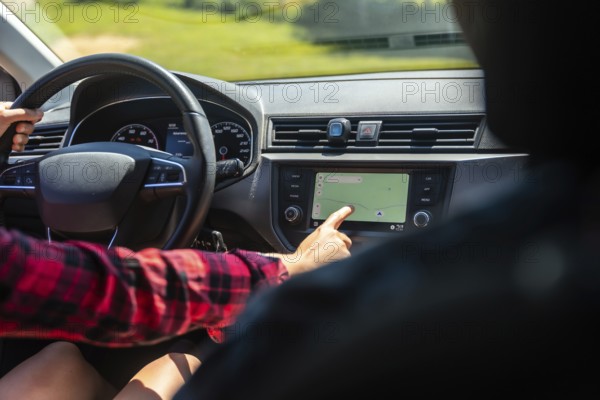 Woman driving a car while interacting with the navigation system on the dashboard's touchscreen