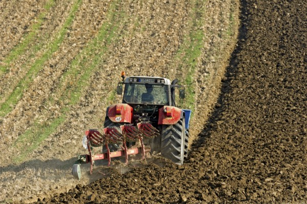 Harvested grain field being turned into a field by Steyr tractor with plough, Hohenpolding, Erding,