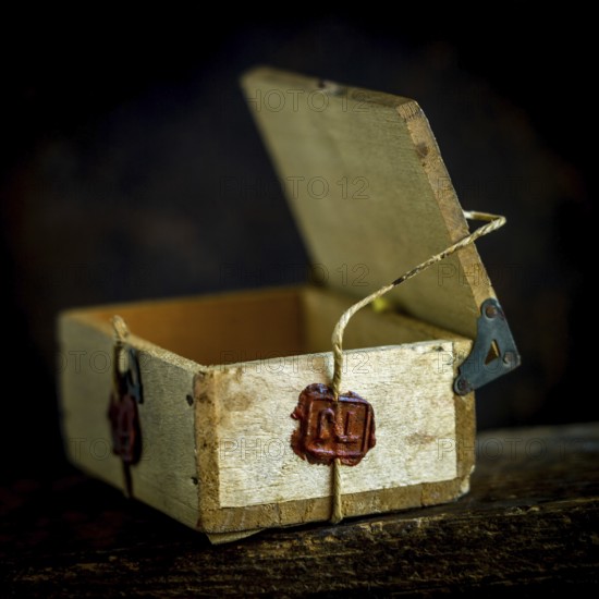 A wooden box is secured with twine, featuring a deep red wax seal that signifies authenticity and