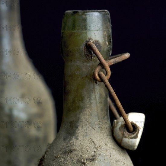 Three dusty vintage bottles stand together, covered in grime, highlighting their age and history.